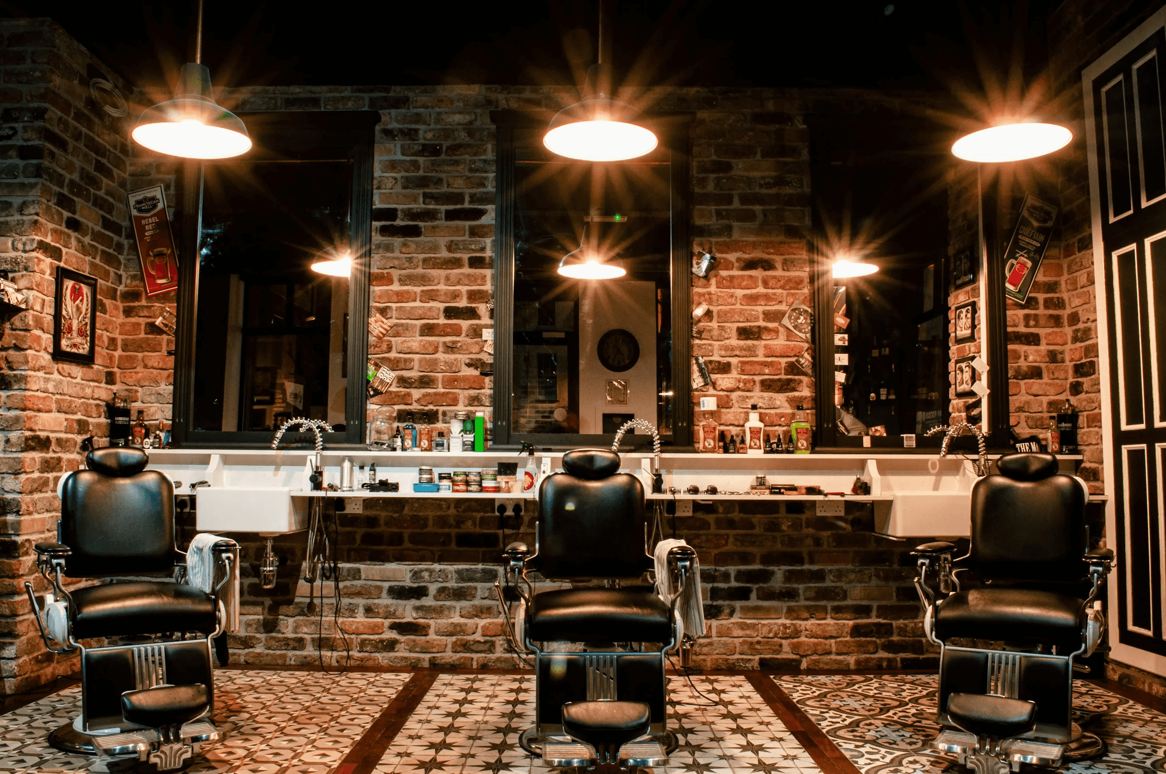 Northside Barbers interior: three black leather barber chairs facing mirrors on an exposed brick wall under warm pendant lights.